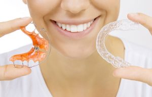 woman holding clear aligner and reainter