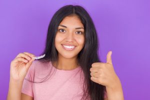 teen girl holding a clear aligner